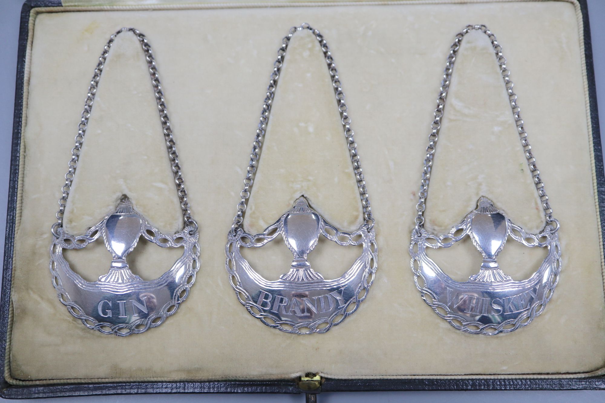 A cased set of three silver wine labels by Daniel & John Wellby, London, 1911, 5cm, 29 grams,